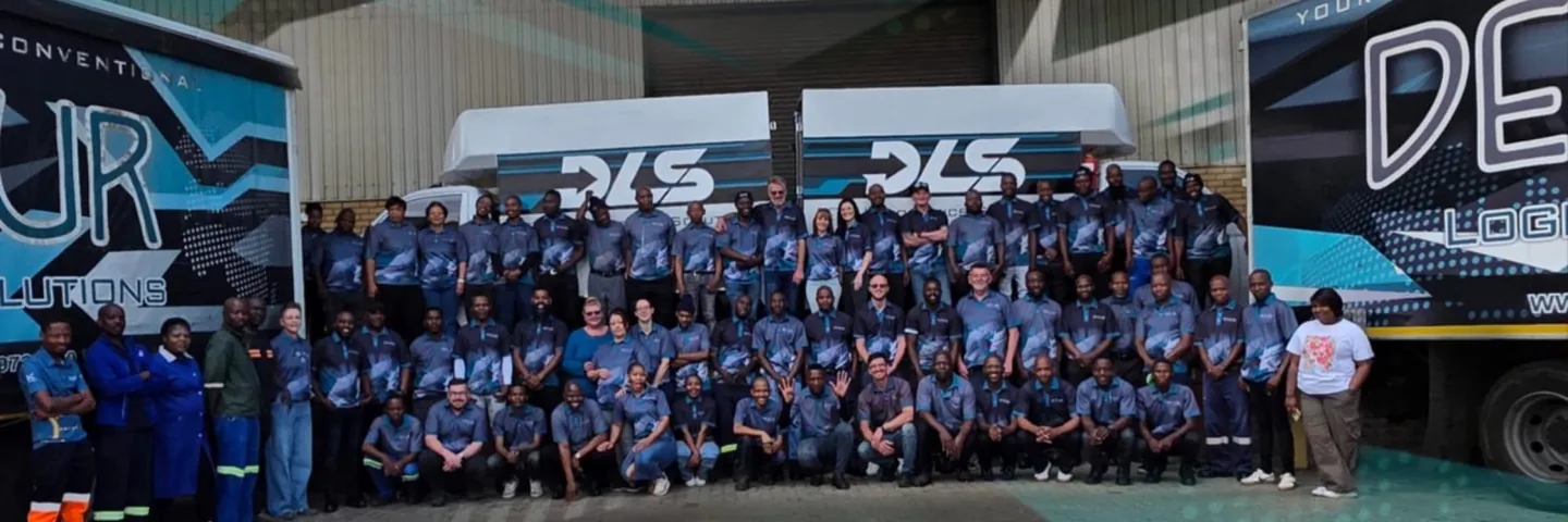The DLS team gathered at the depot in front of liveried delivery vehicles.